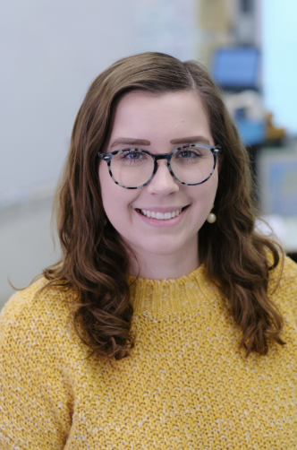 brunette with glasses wearing yellow blouse, smiling